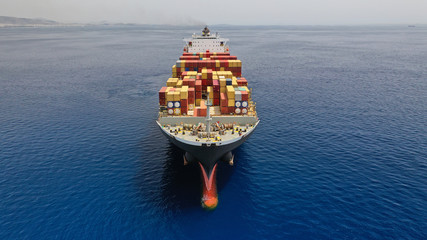 Aerial drone photo of huge colourful truck size container cargo ship cruising open ocean sea