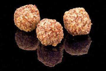 Tasty truffles balls with walnuts, isolated on black background, with reflection