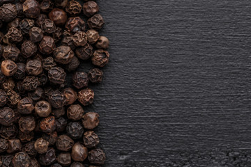 Peppercorn background. Dry black pepper seeds. Top view.On a black background. free space for your text.