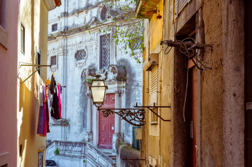 Street lamp and laundry in a picturesque narrow street of Alfama in the old town of Lisbon, Portugal