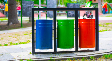 Containers for different types of garbage in red, blue and green in the playground.