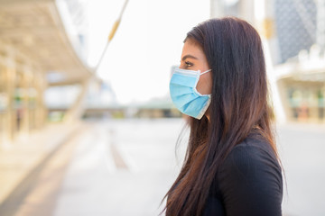 Closeup profile view of young Indian woman with mask for protection from corona virus outbreak in...