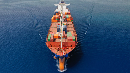 Aerial drone photo of huge colourful truck size container cargo ship cruising open ocean sea