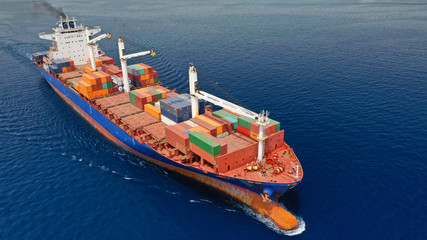 Aerial drone photo of huge colourful truck size container cargo ship cruising open ocean sea