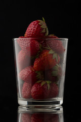 delicious fresh and ripe strawberries in a transparent glass on a black background