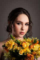 Bride in white dress with bouquet in photostudio