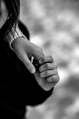 Close up cropped image loving tender older sister gently touch hands of little sister. Friendship and love concept between sisters. Black and white photo.