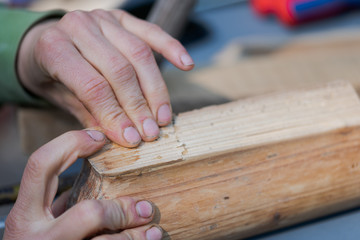 Human hands pressing two pieces of old wooden furniture together that were glued with bone glue