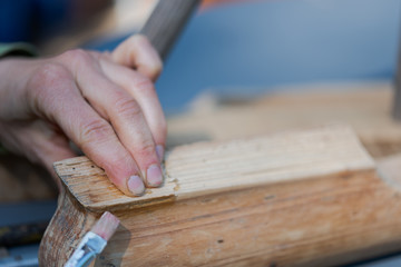 Human hands applying bone glue with brush on piece of old wooden furniture