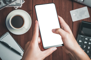 Close up of female hands holding modern smartphone with white blank screen in office at workplace.