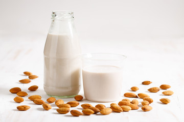 Almond milk in glass bottle with fresh almond nuts.