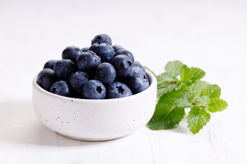 fresh blueberries in ceramics bowl with mint leaves.