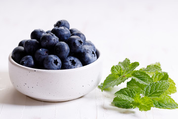 fresh blueberries in ceramics bowl with mint leaves.