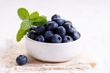 fresh blueberries in ceramics bowl with mint leaves.