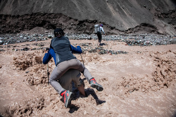 A man carries a woman on his back. Tourists at the foot of the mountain. Hiking. Lefestyle.