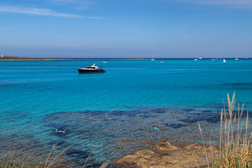 Fototapeta premium Seascape with two people snorkelling in the sea in the foreground, boats and yachts in the background. Active holidays in Sardinia, Italy.
