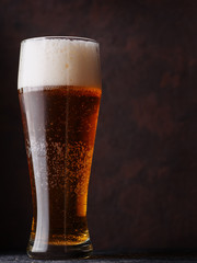 A tall glass of beer on a brown background