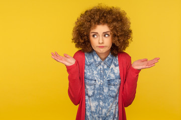 Don't know, maybe. Portrait of clueless uncertain confused woman with fluffy curly hair raising hands in hesitations, doubting and thinking careless, indifferent to question. indoor studio shot