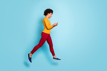 Fototapeta na wymiar Full length body size profile side view of her she nice attractive addicted focused cheerful wavy-haired girl jumping walking using 5g isolated on bright vivid shine vibrant blue color background