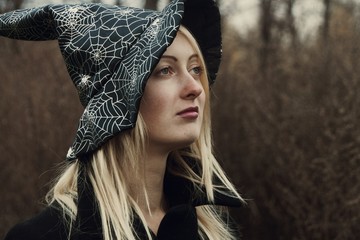 Beautiful woman in witch hat. Girl in halloween costume. Autumn scene