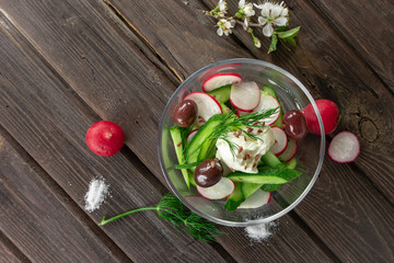 Top view of fresh radish and cucumber salad on wooden background
