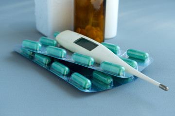 Thermometer, medications and pills on blue background. Healthcare medical doctor concept