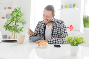 Healthy breakfast vitamins energy concept. Positive cheerful guy sit kitchen table eat cornflakes muesli fruit sweet porridge hold spoon in modern apartment