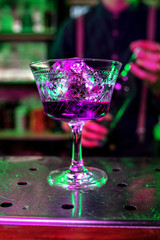 Close up of alcoholic cocktail, beverage, drink, prepared by professional barman in multicolored neon light. Entertainment, drinks, service concept. Modern bar, trendy neoned colors, copyspace.