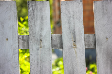 White wooden fence against the background of a garden and blossoming bushes in summer, life in a country house on vacation 