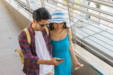 Couple traveler are catching up on news with their phone.