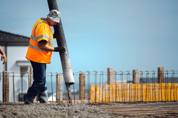 industrial workers pouring cement with automatic pump tube