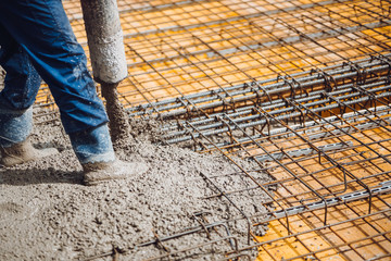 construction worker pouring cement or concrete with pump tube. Reiforced steel bars and rods