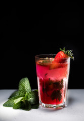 Glass of strawberry drink on a drak background. Fresh strawberry cocktail. Fresh summer cocktail with strawbery, ice and mint.