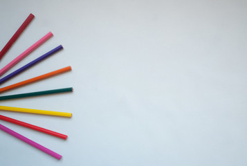 Colored pencils conceptual composition on the light grey background, top view creative flatlay with copyspace for your artwork display or any design