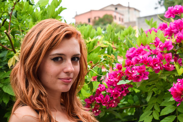 Naklejka premium Orange hair girl with violet Bougainvillea in the background of the garden