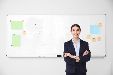 Young teacher near whiteboard in modern classroom. Space for text