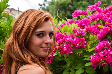 Fototapeta premium Orange hair girl with violet Bougainvillea in the background of the garden