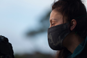 A woman with a mask on a blue sky background during the coronavirus pandemic. New normal