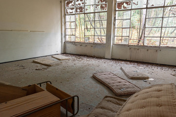 Old abandoned and decay mattresses bed in abandoned building room in Italy house in the wood with windows and forest outside