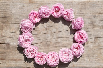 Vintage background pink roses in wreath on a wooden board 
