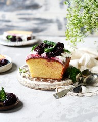 Cake with cream and blackberries on the plate on a gray background, still life