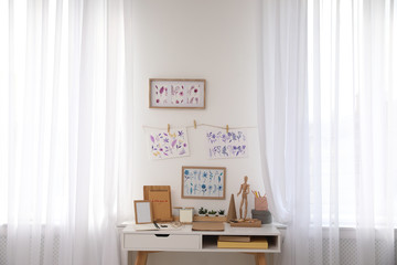 Stylish room interior with creative workplace near white wall