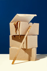 Creative composition of three paper eco boxes package and chopsticks on blue background.Concept of delivery restaurant and asian take away food