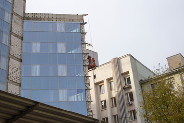 A man insulates the walls of a building with a modern ventilated facade. The concept of frost...