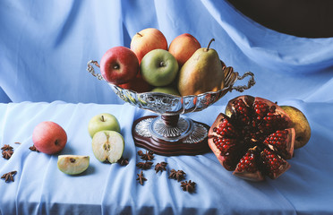 still life with pomegranate and apples on a dark background