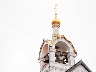 Beautiful white church with a cross and a dome. Big bells against the sky, catholic religion