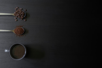 Direct above view of roasted coffee beans, freshly ground coffee and cup with black coffee on dark brown background