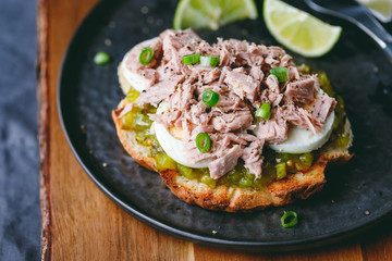 Open sandwich with canned tuna, egg and pickled cucumber dressing served with lime.