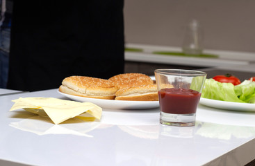 The ingredients are in the kitchen in the form of cheese, salad, tomato and burger rolls. Cooking Burgers at Home, Background