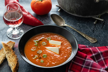 Rustic tomato soup with white cheese in black bowl